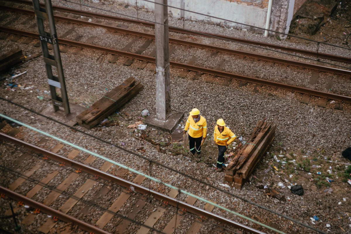 Zwei Arbeiter in gelber Wetterkleidung neben Gleisen, von oben gesehen