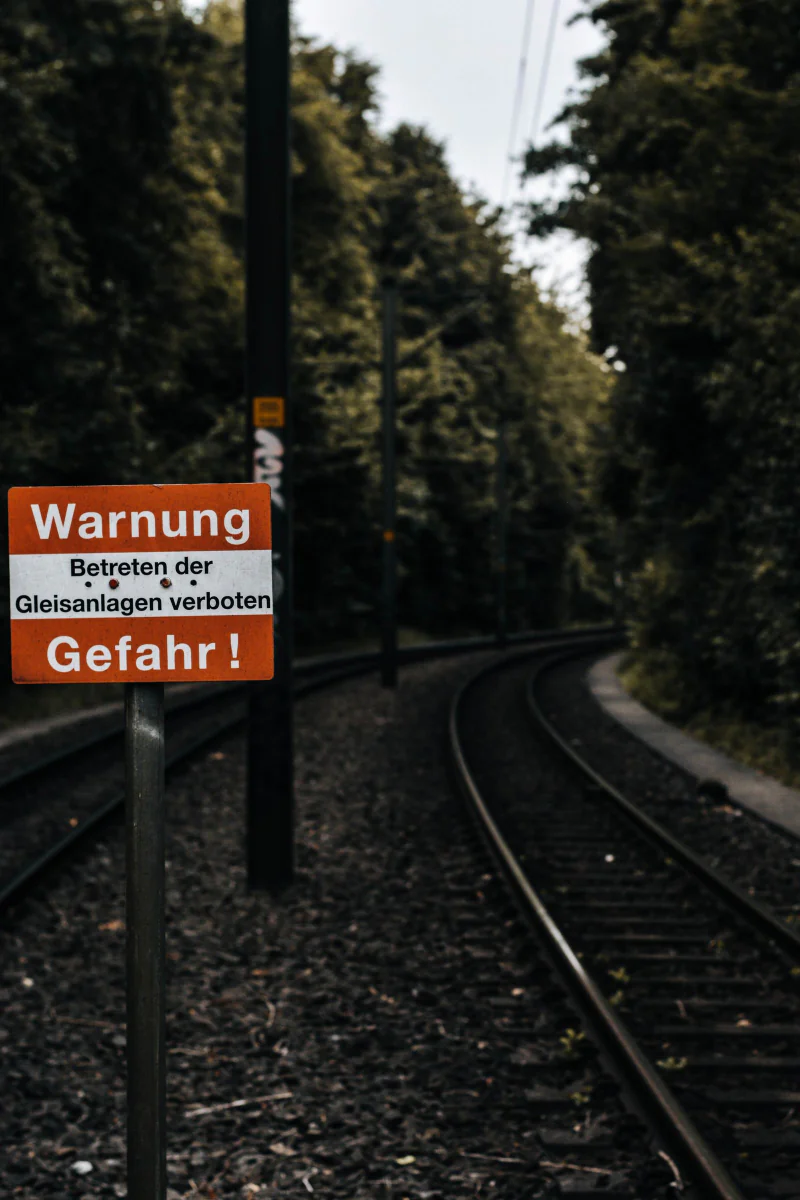 Warnschild „Betreten der Gleisanlagen verboten, Gefahr“ an einer Strecke im Wald