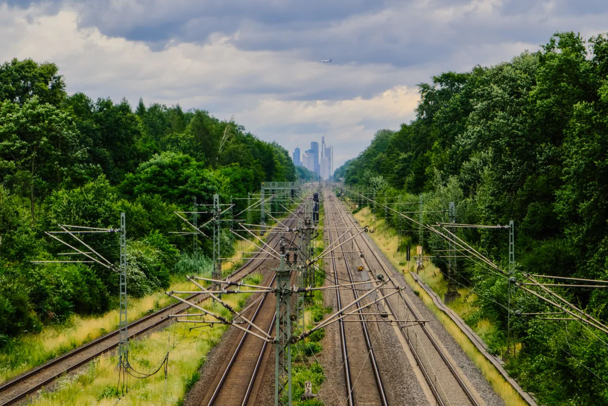 Mehrgleisige Bahnstrecke mit Oberleitung in einem Grünzug