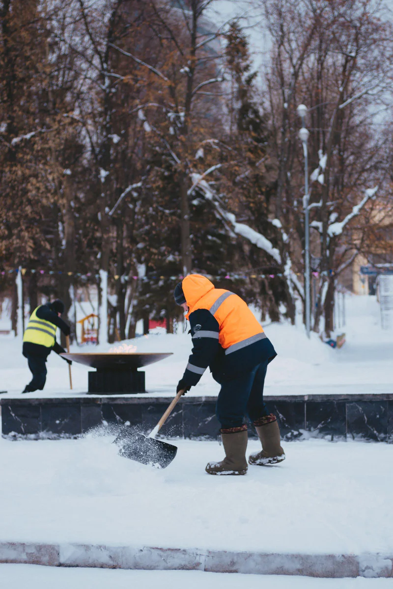 Zwei Arbeiter in oranger Kleidung räumen Schnee